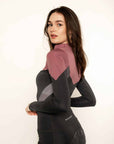 Brunette model wearing pink and grey base layer top and grey riding leggings.