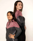 Young child rider and adult rider wearing pink and grey two tone base layer with grey leggings .