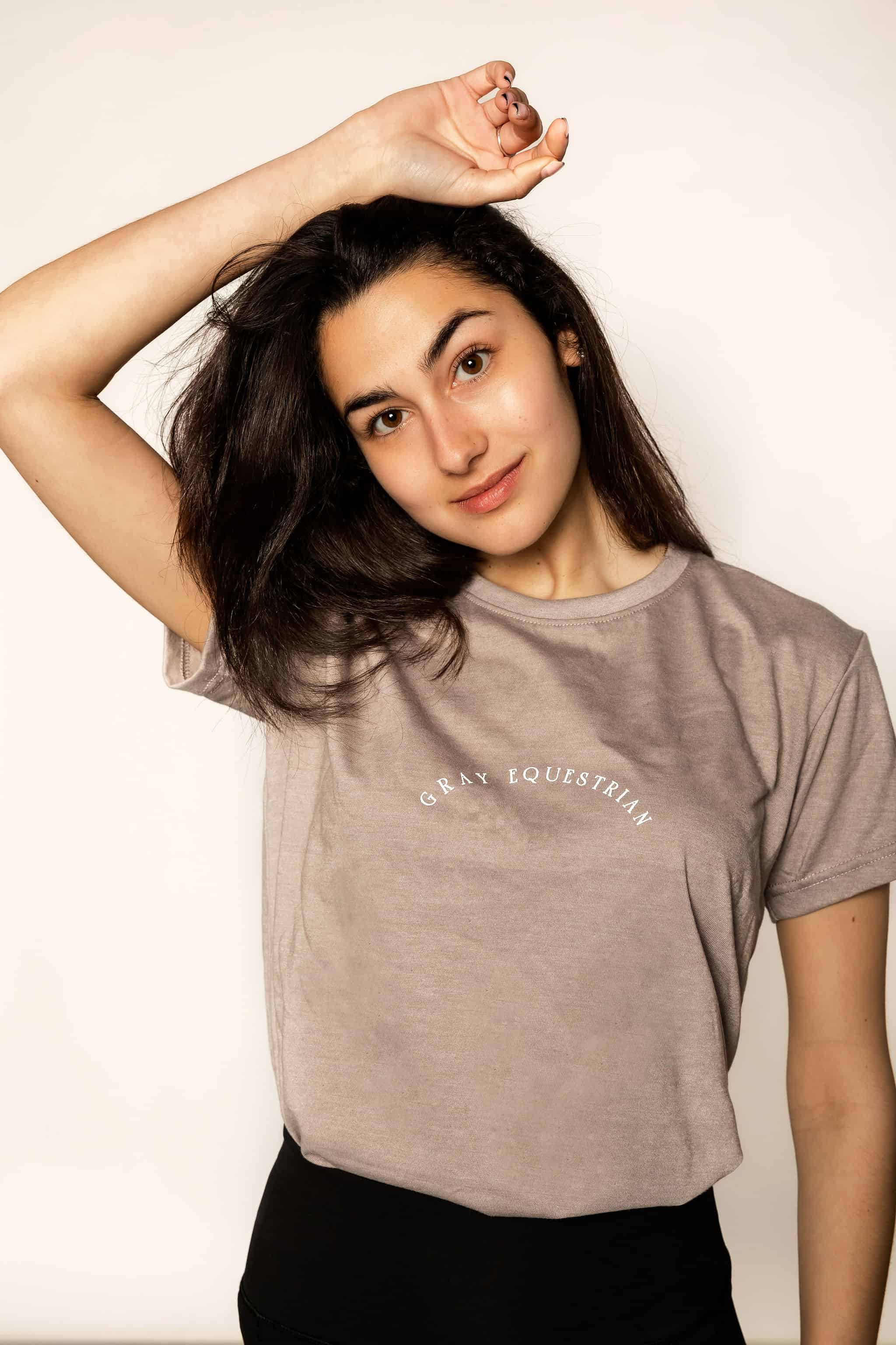 Brunette model wearing grey cotton t shirt with her hand above her head