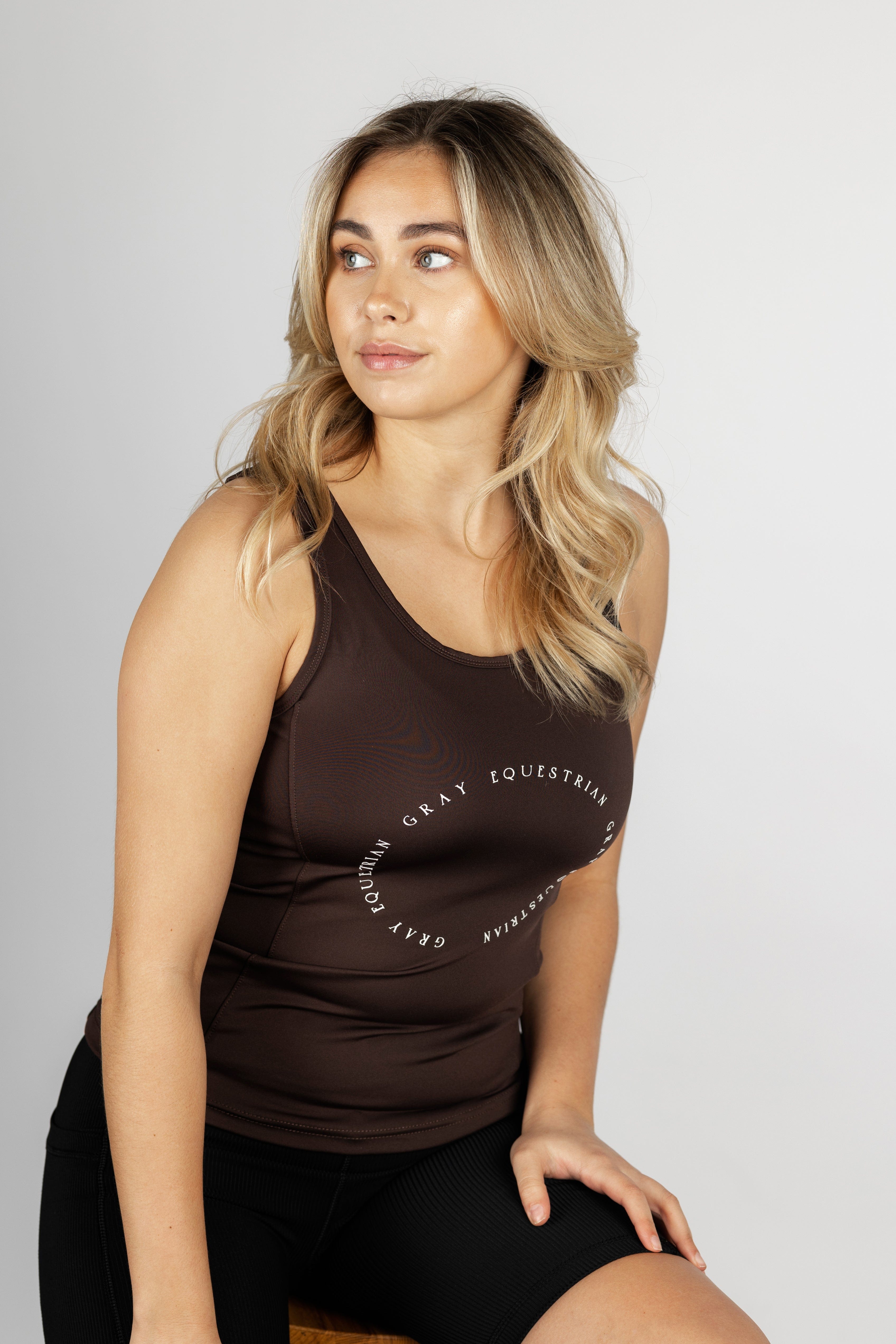 A blonde model wearing our brown scoop neck equestrian vest in a tight-fitting breathable fabric.