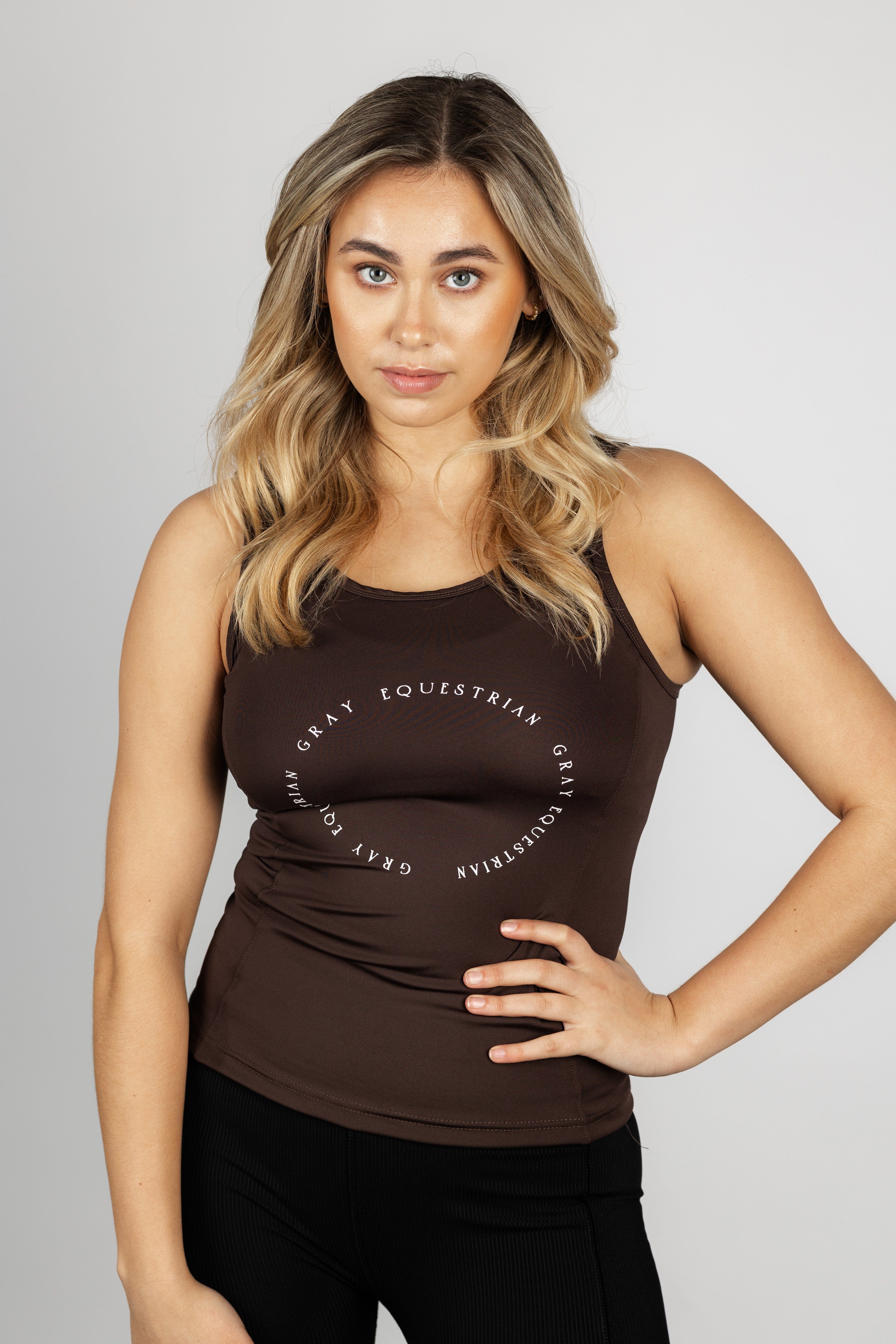 A blonde model wearing our brown scoop neck equestrian vest in a tight-fitting breathable fabric.