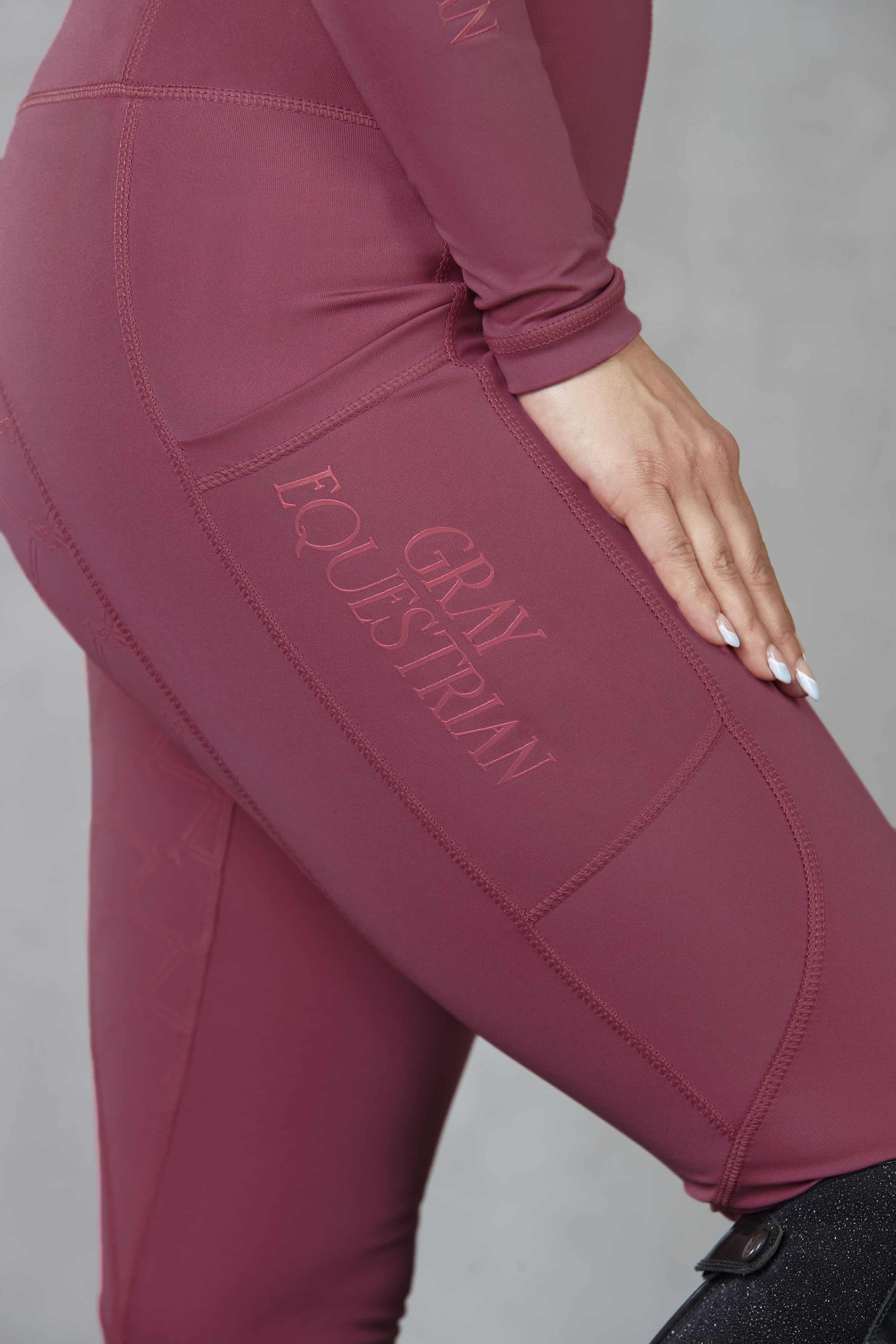 A close up of the gloss Grey Equestrian logo and phone pocket on our fleece-lined berry leggings.