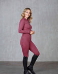 A blonde model wearing our fleece-lined berry leggings with matching long-sleeved 1/4 zip base layer.