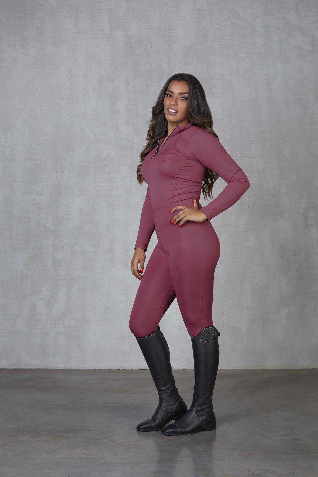 A brunette model wearing our fleece-lined berry leggings with matching long-sleeved 1/4 zip base layer.