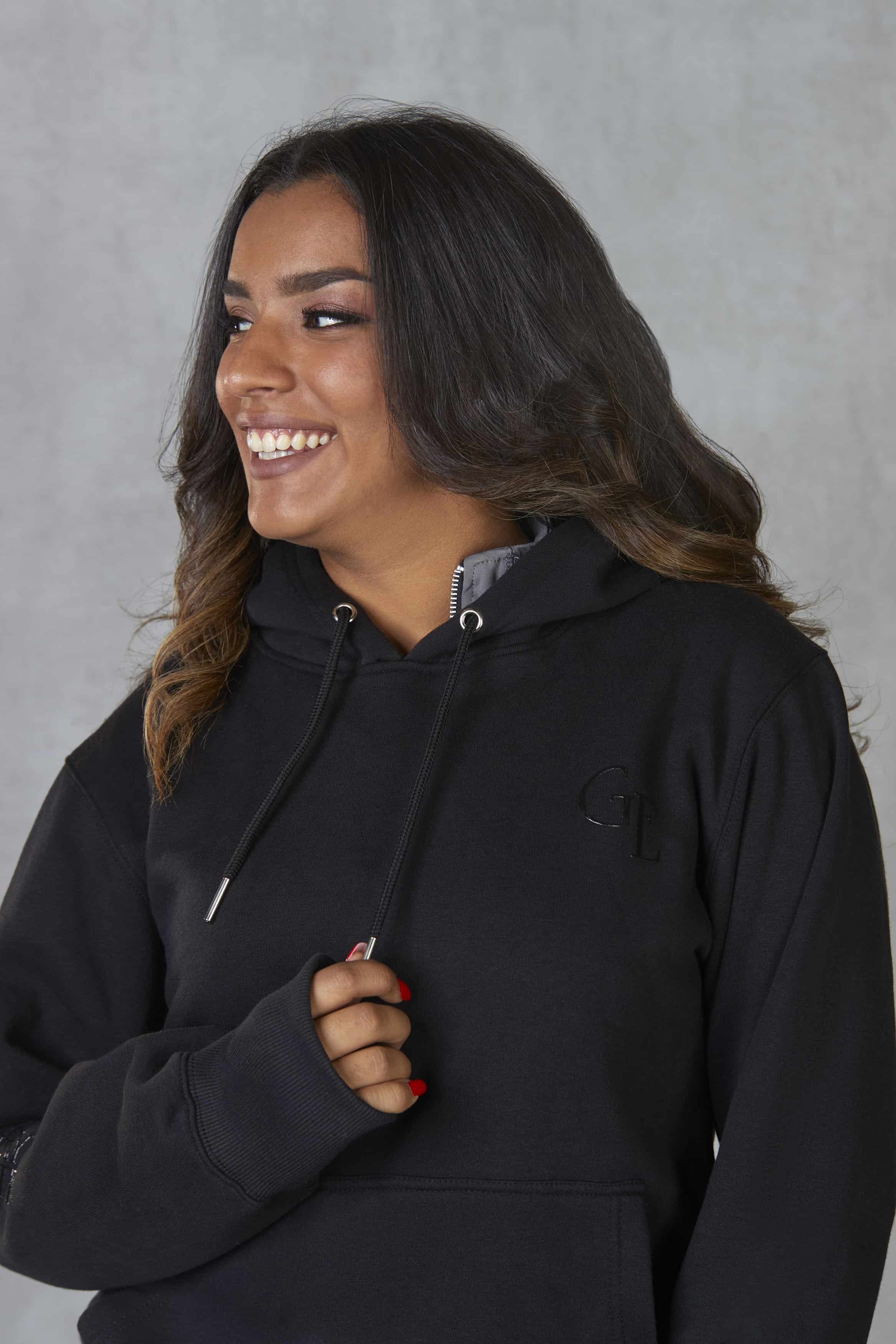 Brunette model wearing our black fleece-lined oversized equestrian hoodie and grey riding leggings.