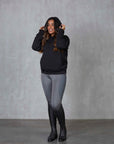Brunette model wearing our black fleece-lined oversized equestrian hoodie and grey riding leggings.