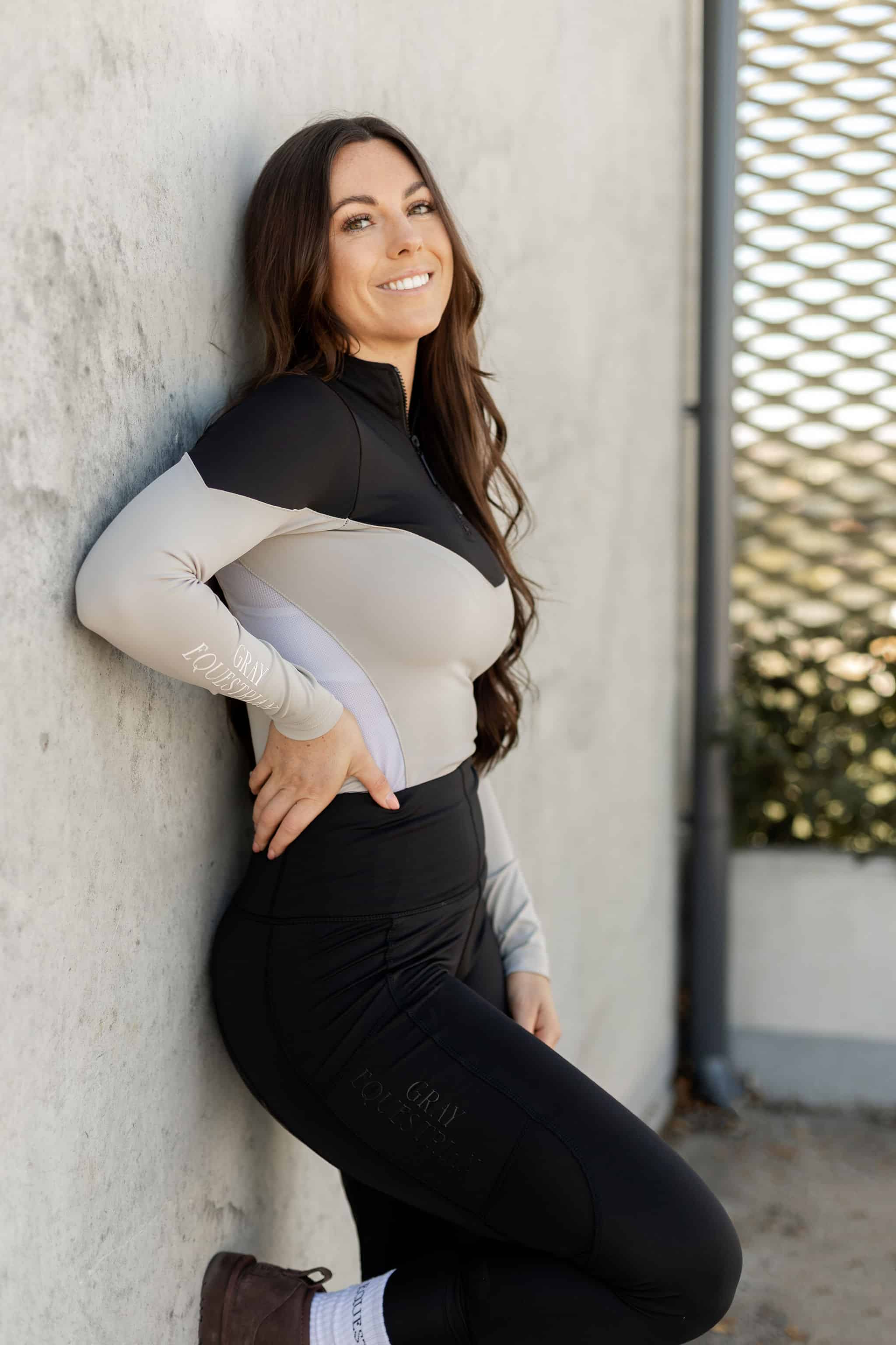 Brunette model wearing our long-sleeved black and grey two toned base layer.