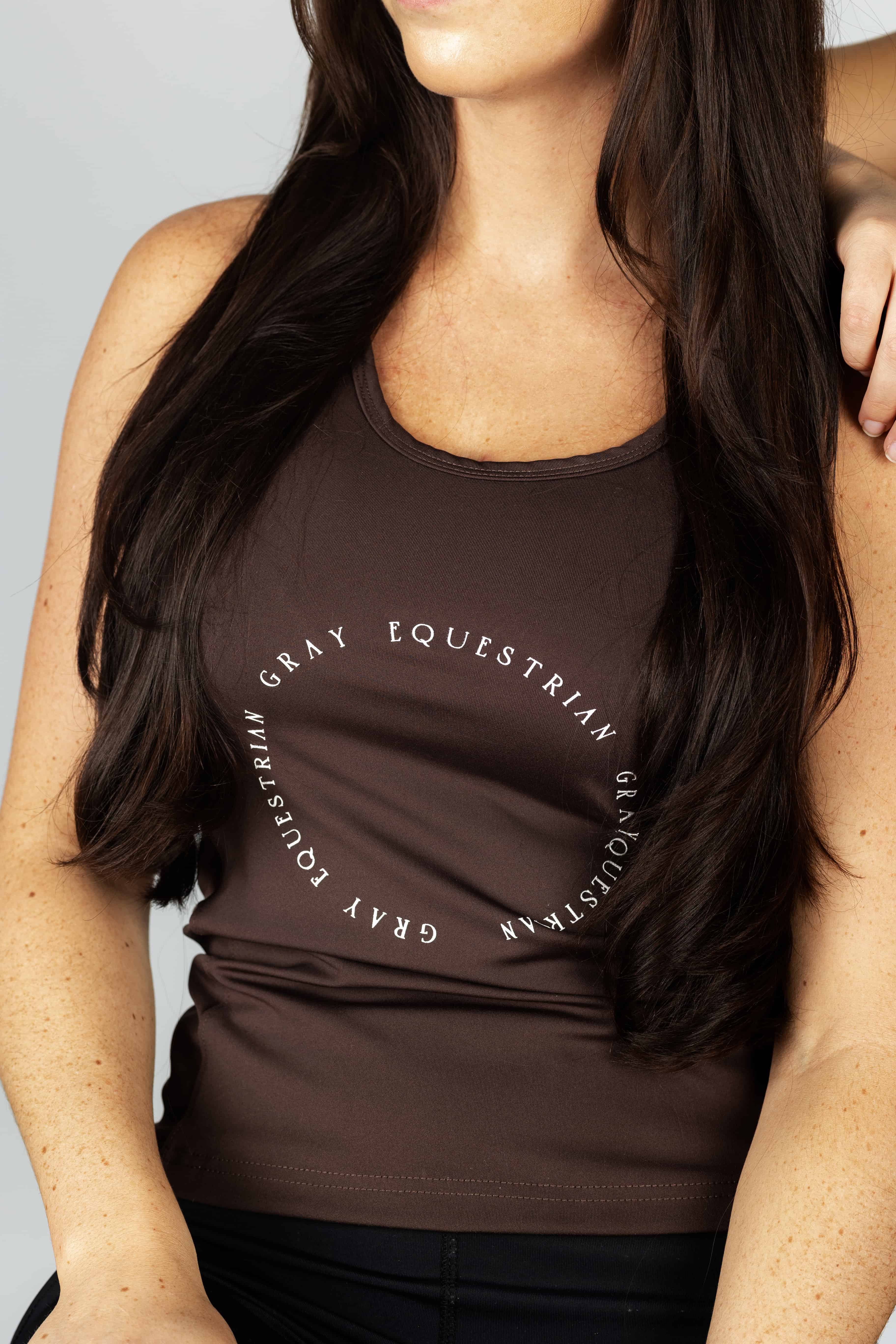 A brunette model wearing our brown scoop neck equestrian vest in a tight-fitting breathable fabric.