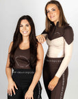 A brunette model wearing our scoop neck brown equestrian vest. With a second brunette model wearing our brown and cream two toned 1/4 zip base layer.