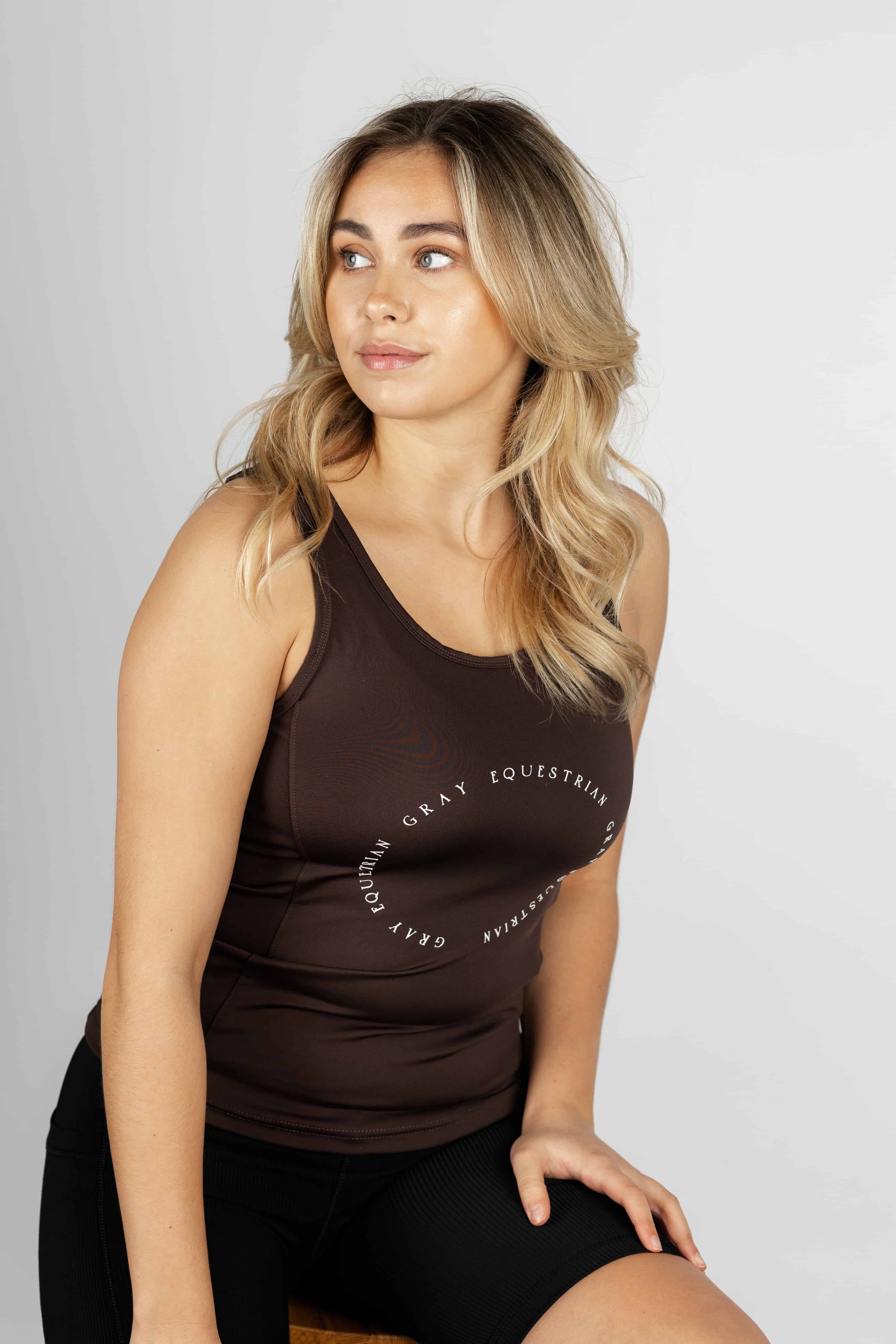 A blonde model wearing our brown scoop neck equestrian vest in a tight-fitting breathable fabric.
