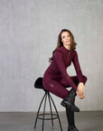 Brunette model wearing our burgundy equestrian leggings and matching long sleeved base layer.