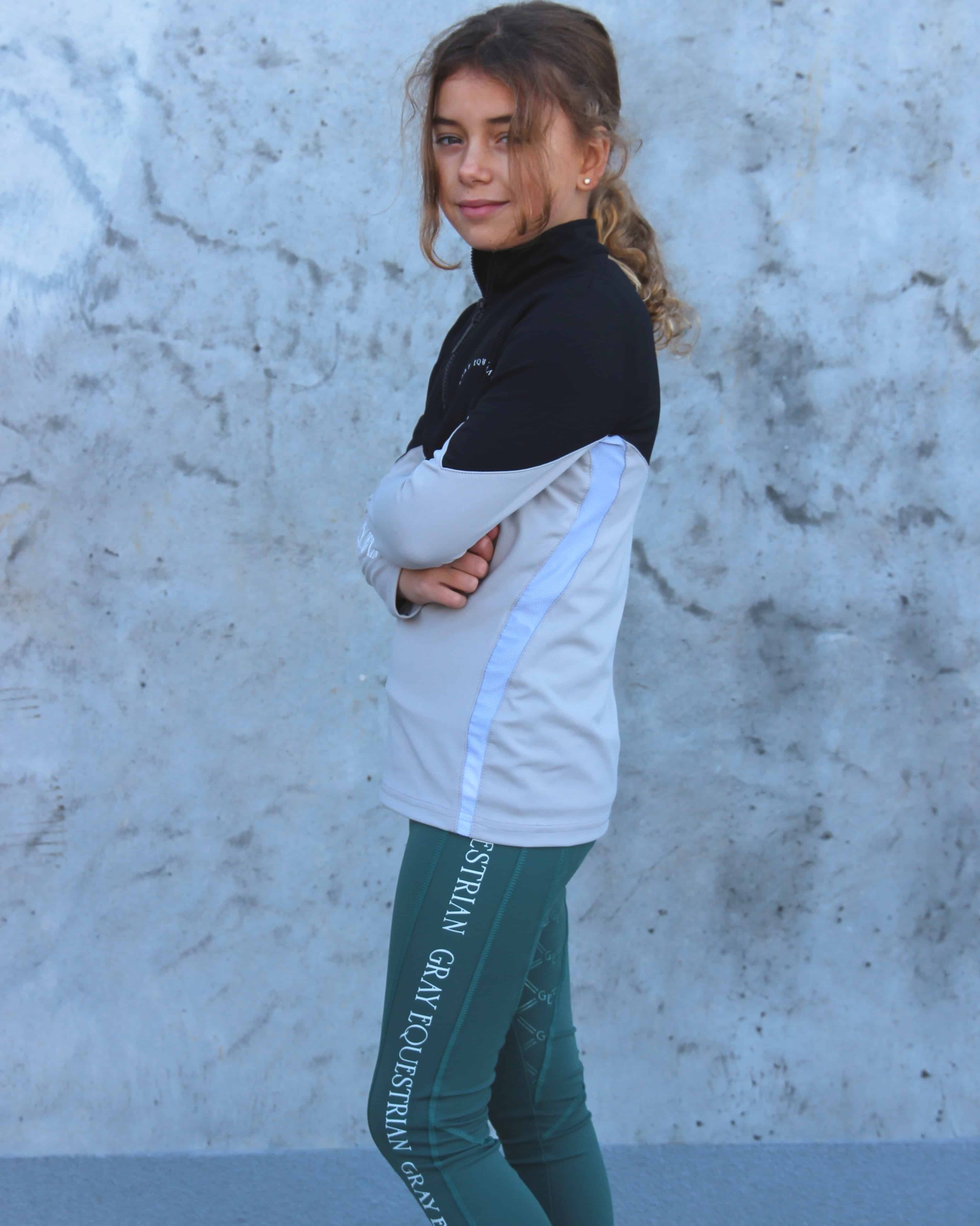 Our child model wearing our black and grey two toned base layer and green riding leggings.