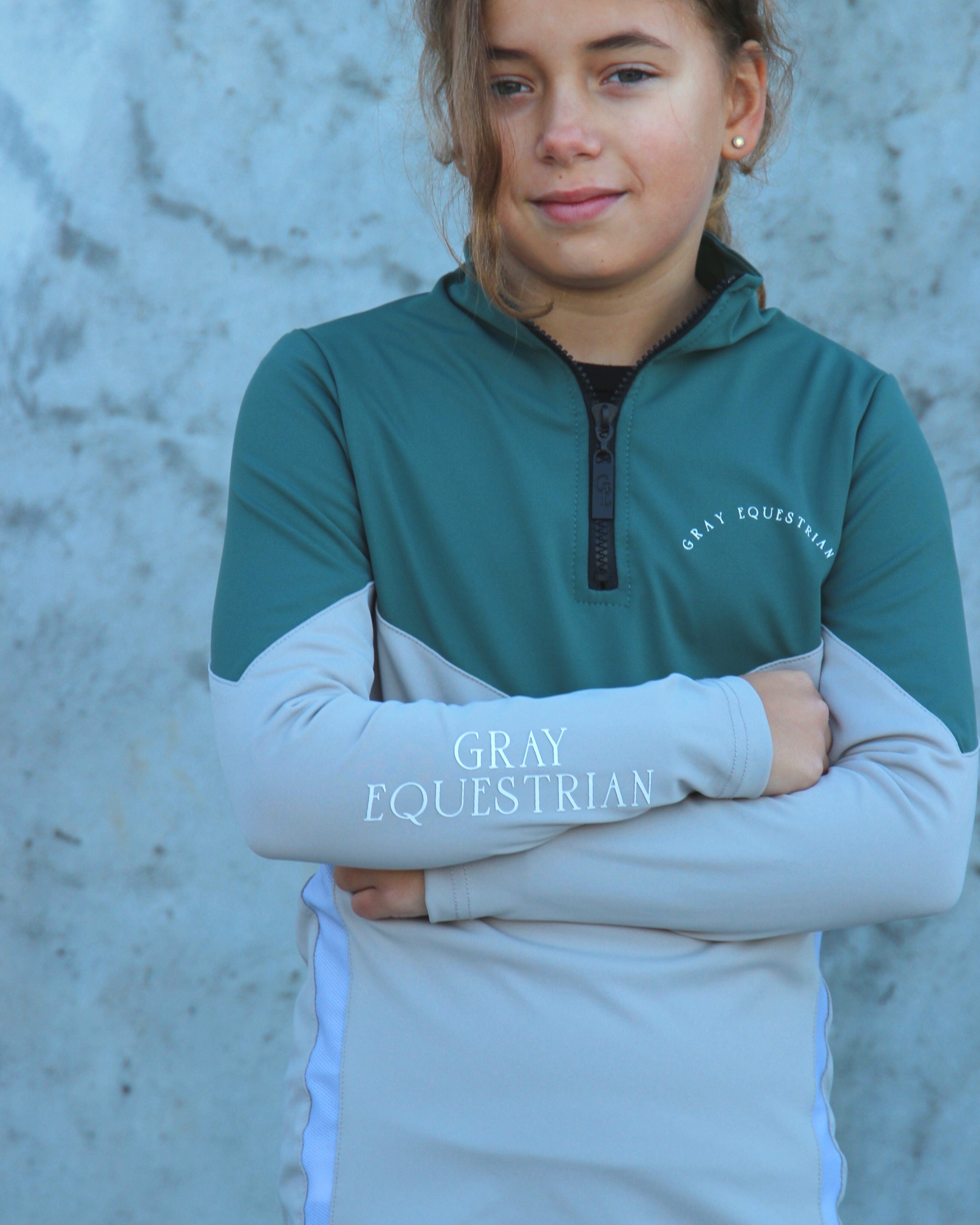 A child model wearing our our green and grey base layer with black leggings.