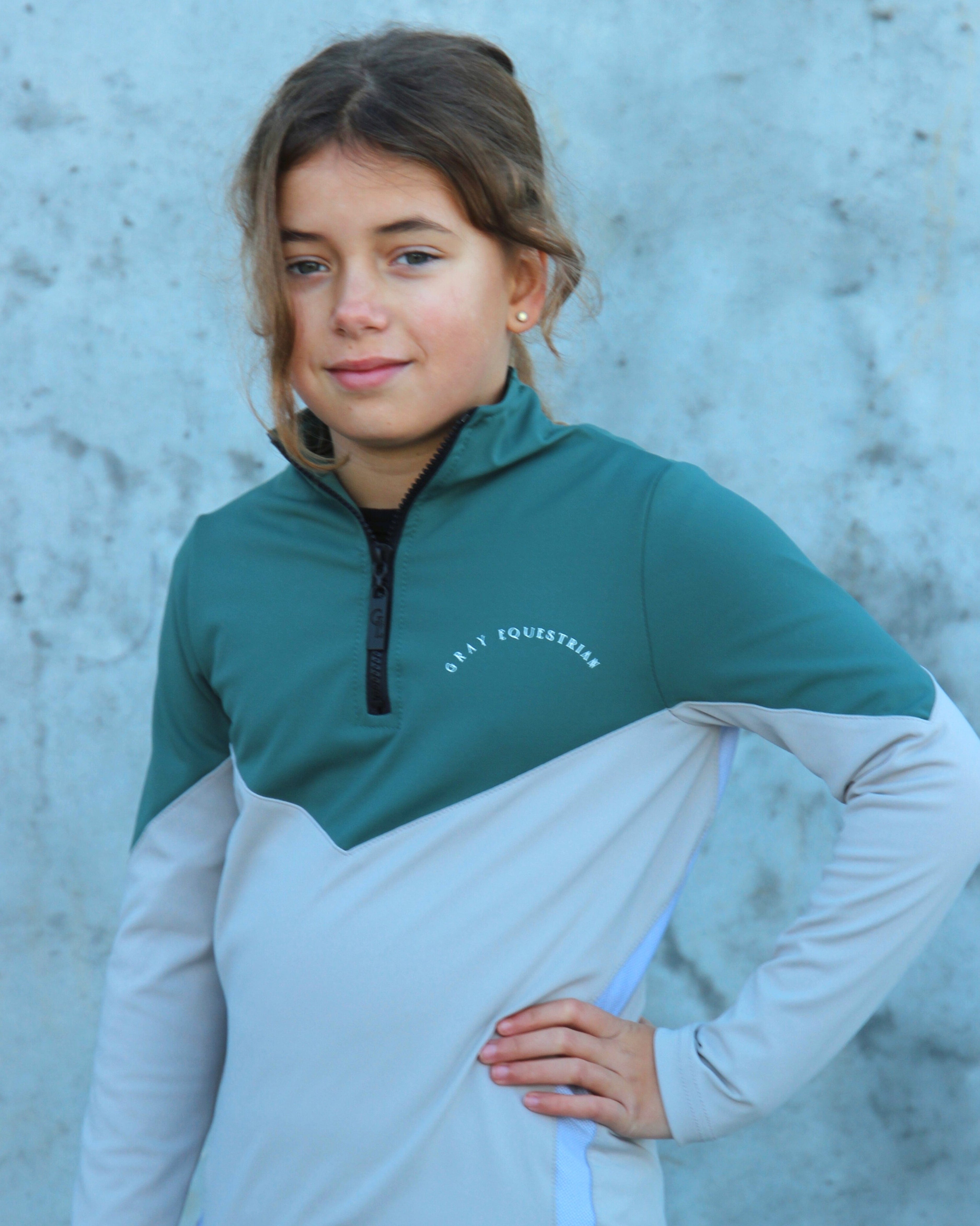 A child model wearing our our green and grey base layer with black leggings.