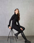 A brunette model wearing our long sleeved black 1/4 zip equestrian base later with matching leggings.