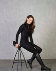 A brunette model wearing our long sleeved black 1/4 zip equestrian base later with matching leggings.