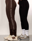 A side-view of two models. The model on the left is wearing our brown fleece-lined leggings that have a white Grey Equestrian detail down the side. The other model is wearing our black fleece lined riding leggings.