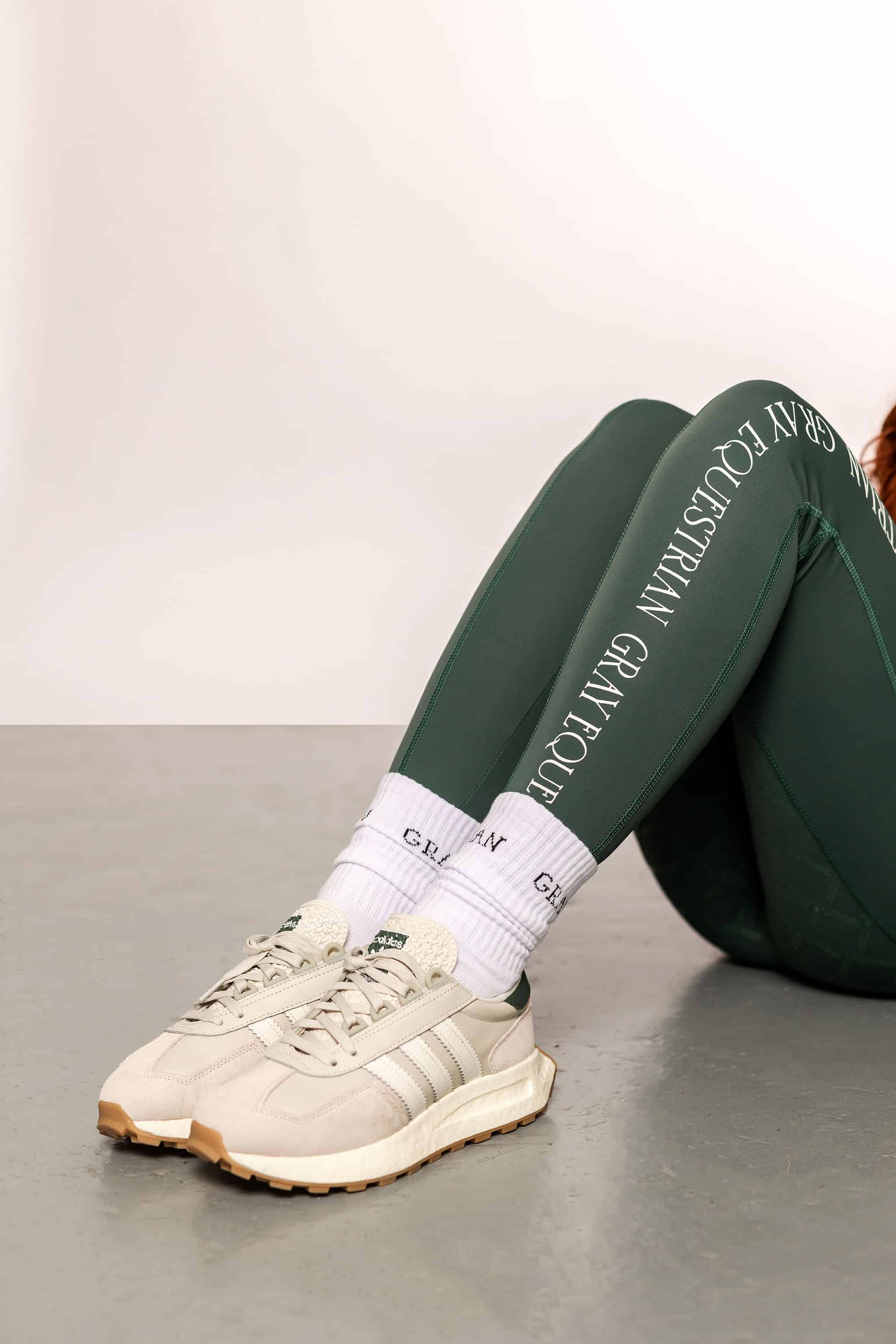 A close up of our green renew riding leggings and white performance socks.