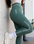 A view of the side of our green riding leggings with phone pocket and white Grey Equestrian branding down the side and waistband.