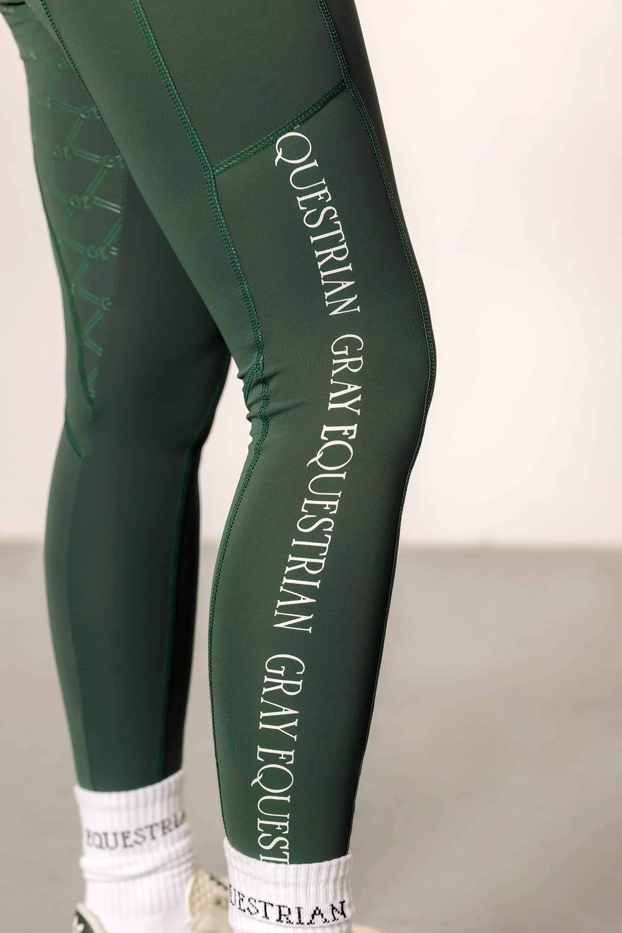 A close-up of the side of our green riding leggings with white GREY EQUESTRIAN detailing.