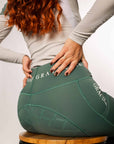 A view of the back of our green riding leggings with full non-slip seat and white Grey Equestrian branding on the waistband.