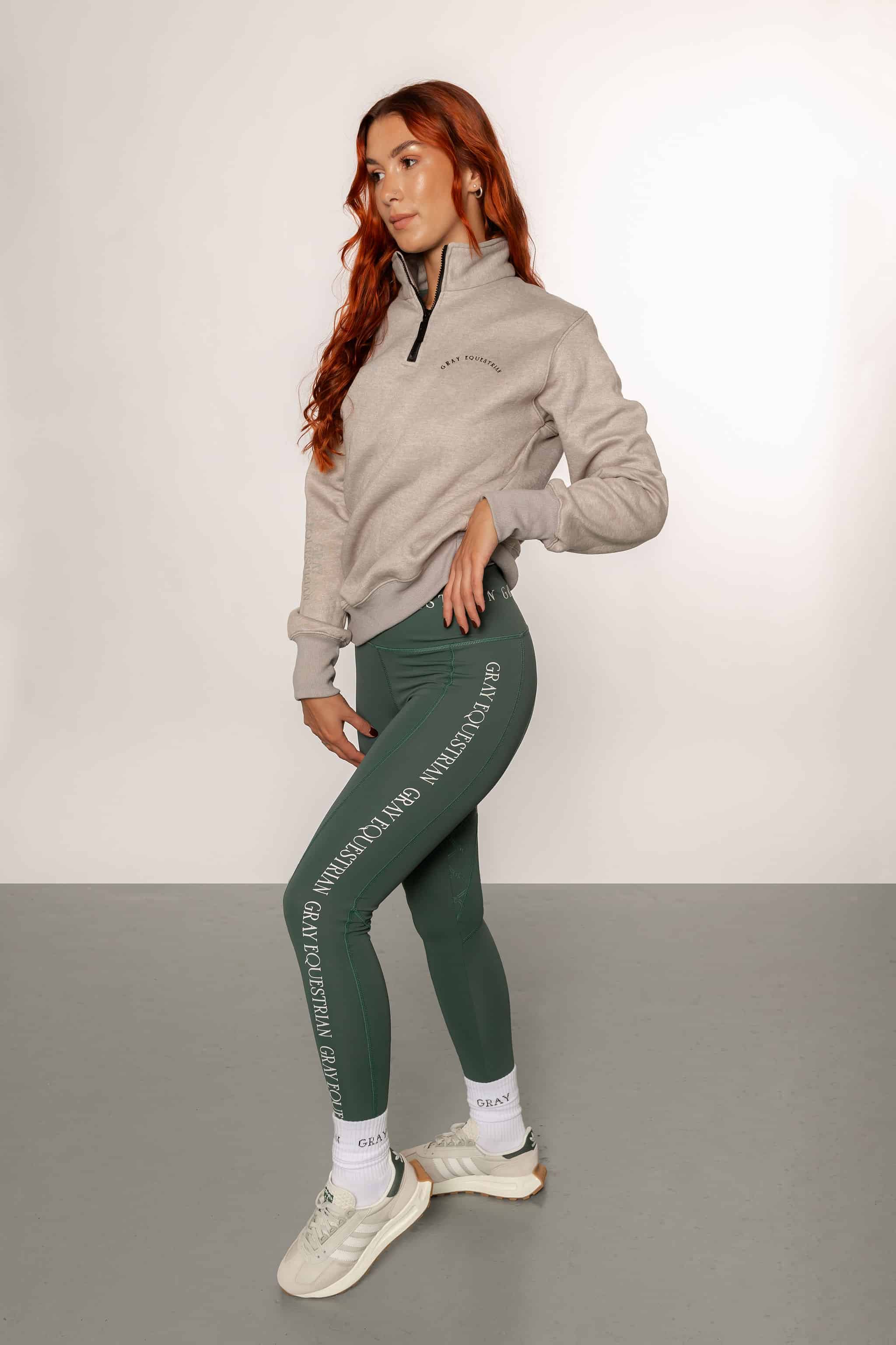 A model wearing our 1/4 zip grey jumper and green riding leggings.