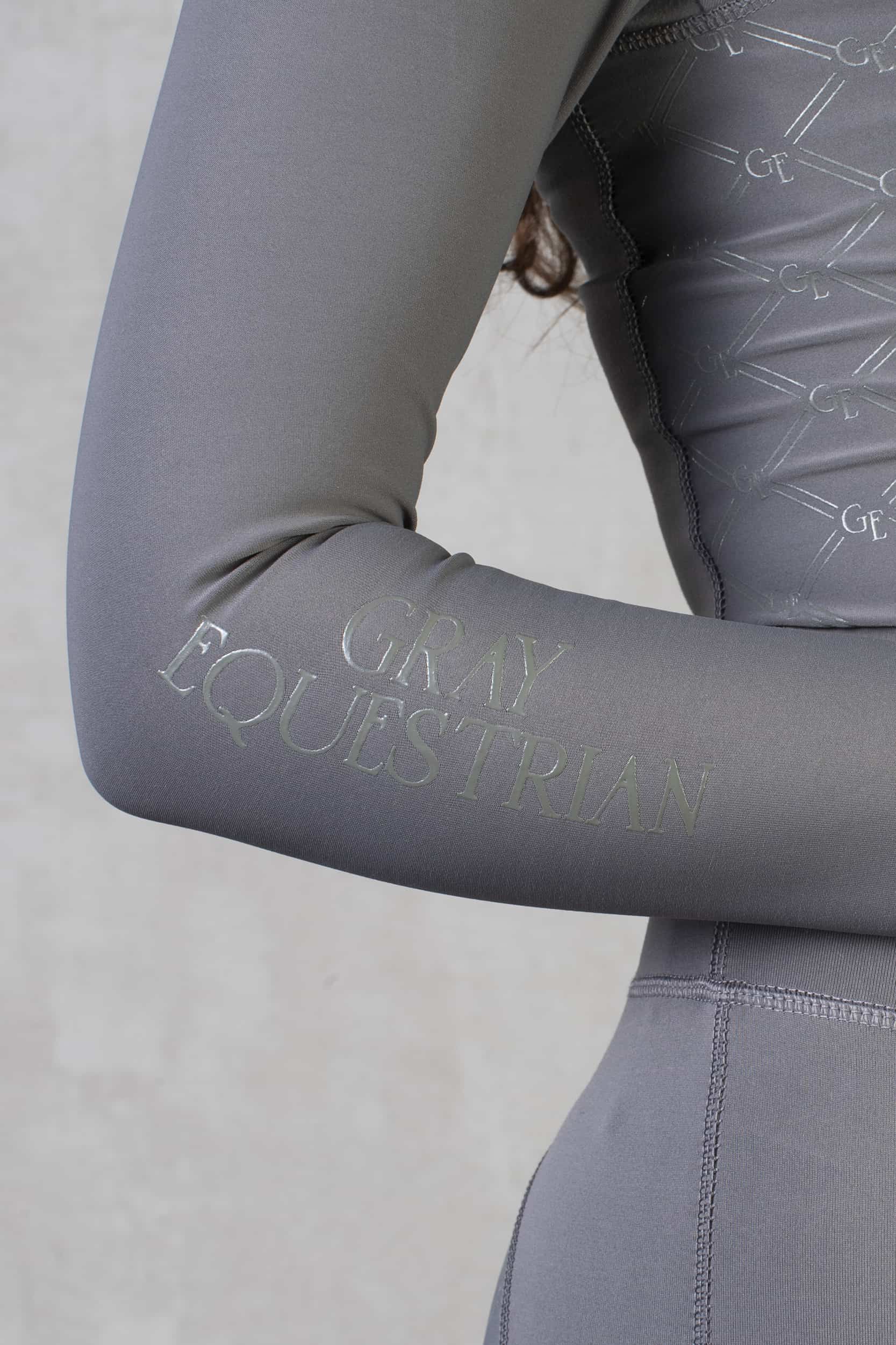 A close up of the minimal Grey Equestrian branding on the sleeve of our grey base layer.