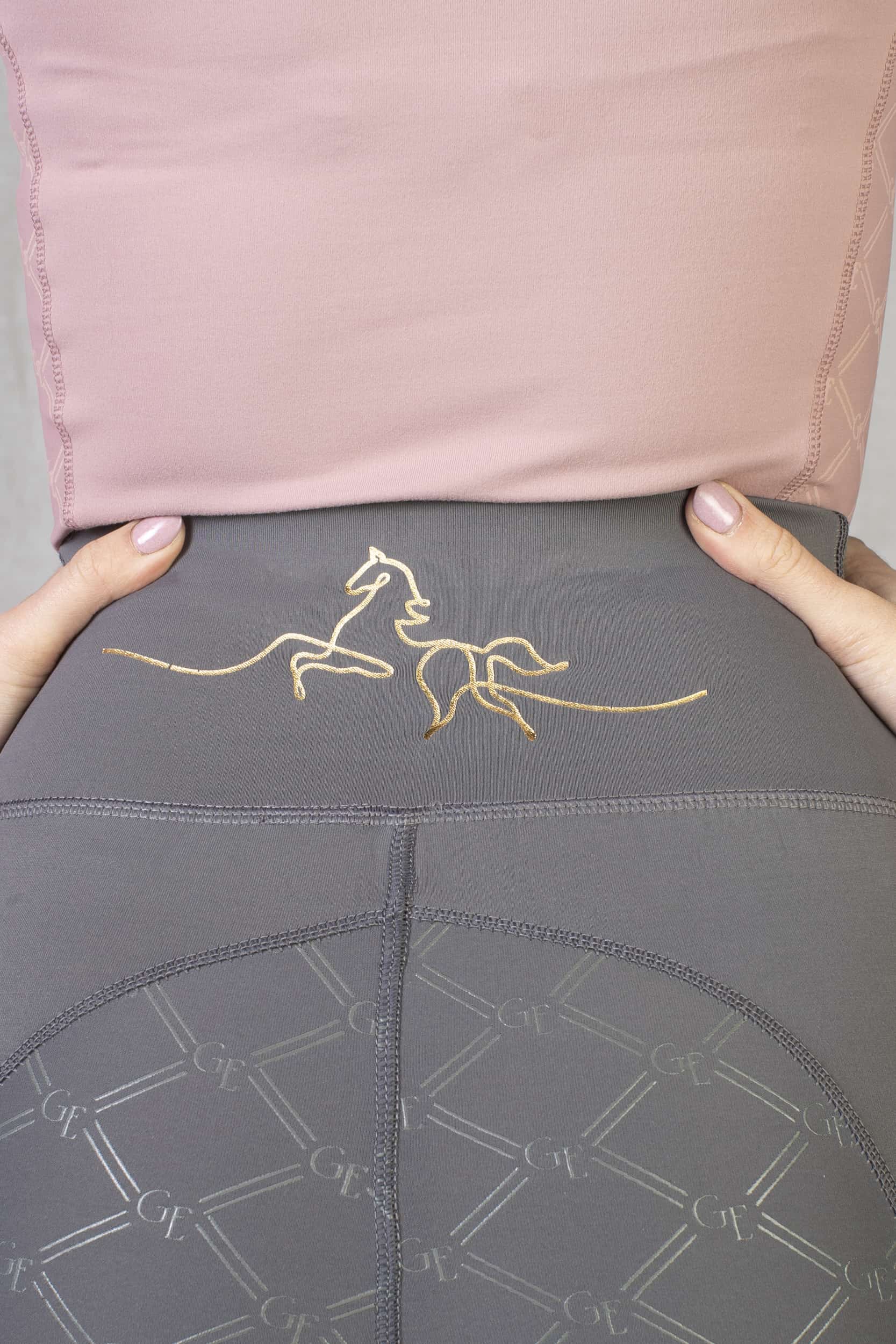 A view of the minimal gold horse detailing on the back waistband of our grey leggings.