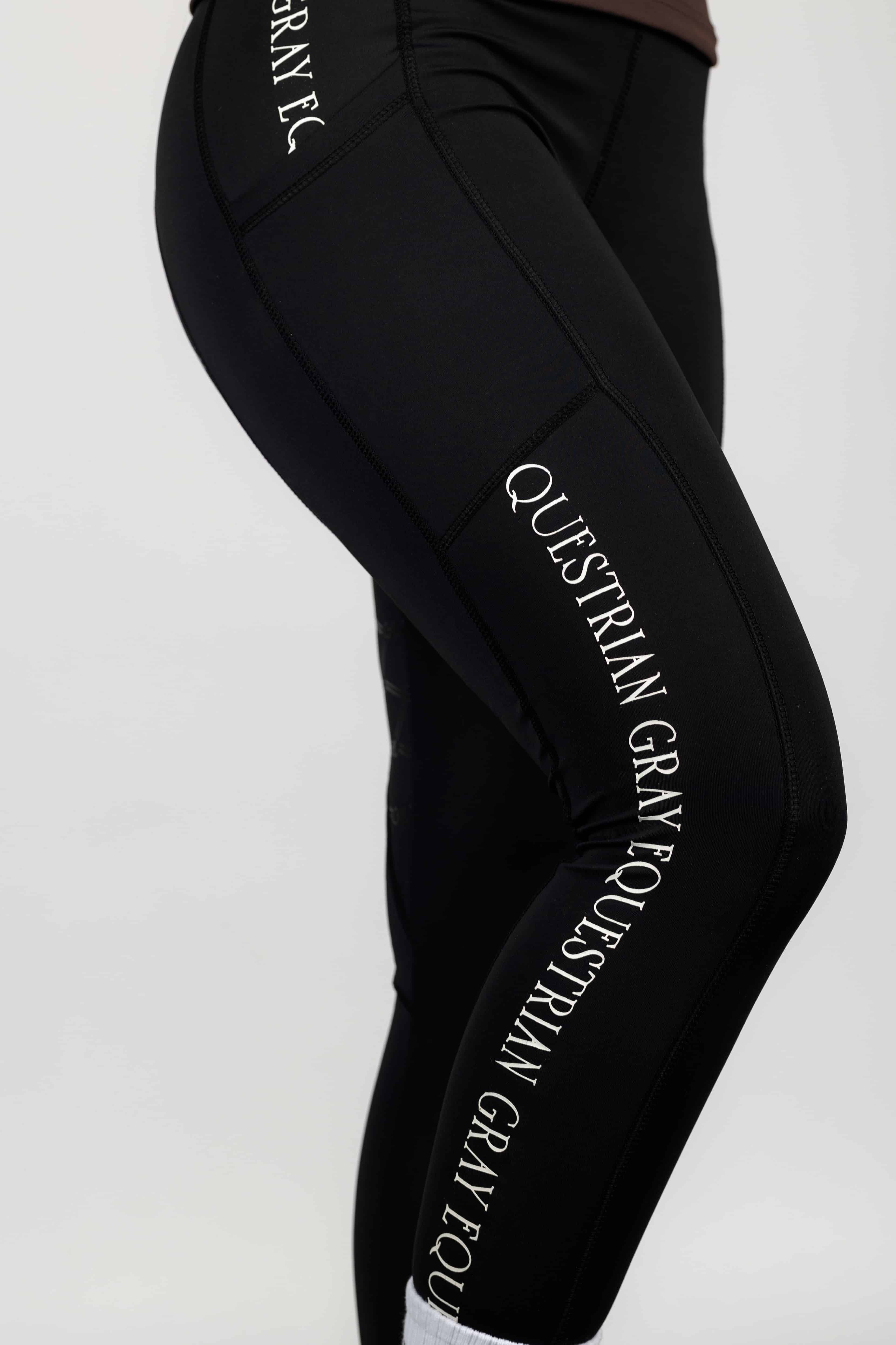 A close up of the subtle white Grey Equestrian branding on our black renew riding leggings.
