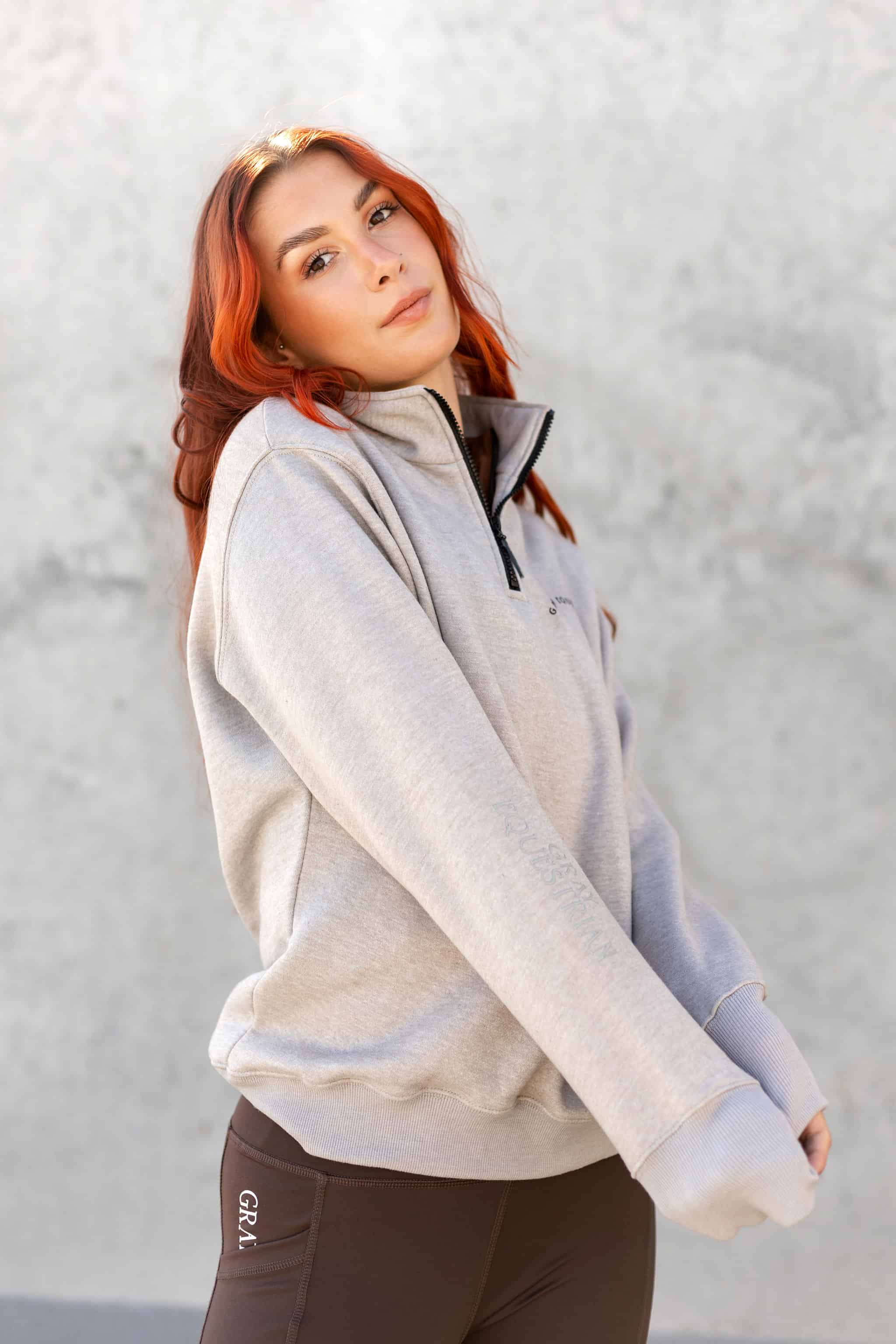 A model wearing our taupe grey 1/4 zip sweatshirt and green riding leggings.