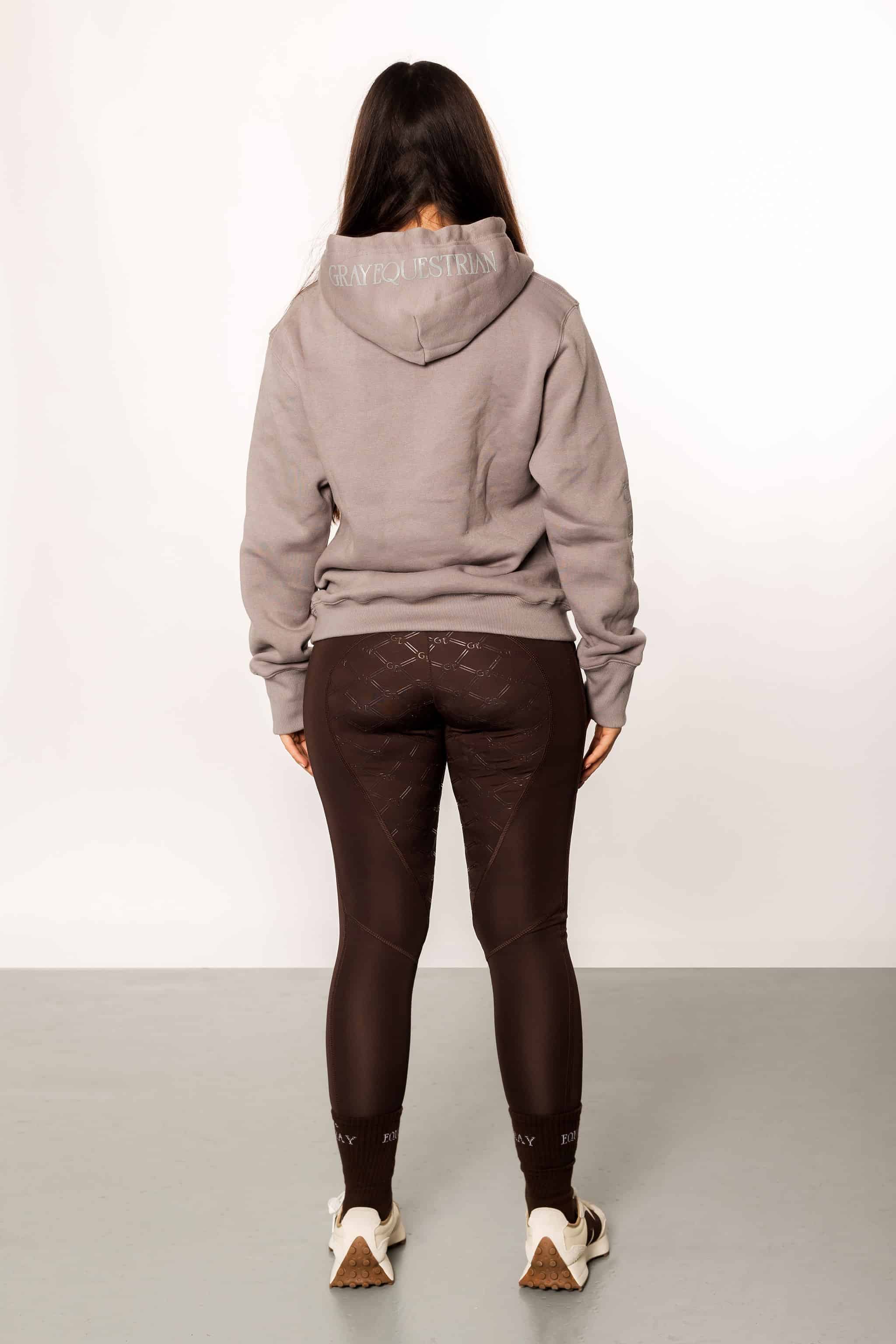 A model wearing our taupe grey hoodie and brown riding leggings.